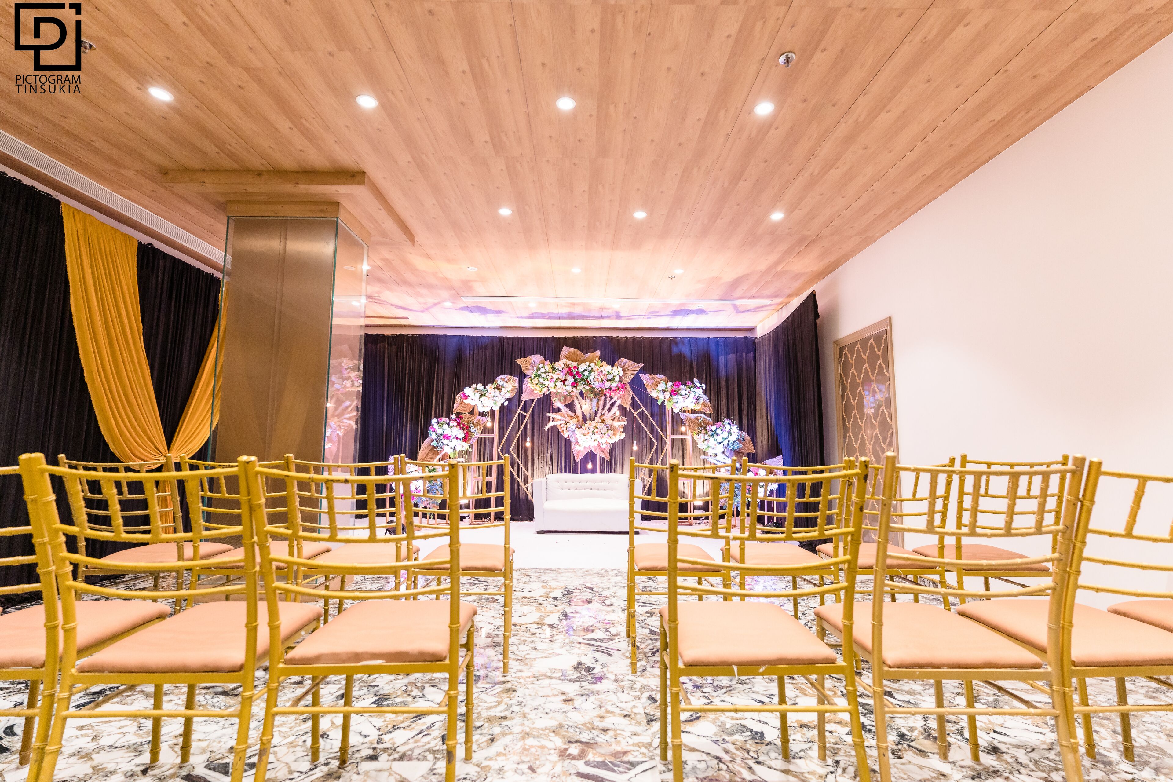Une salle avec une scène, des chaises et une composition florale.