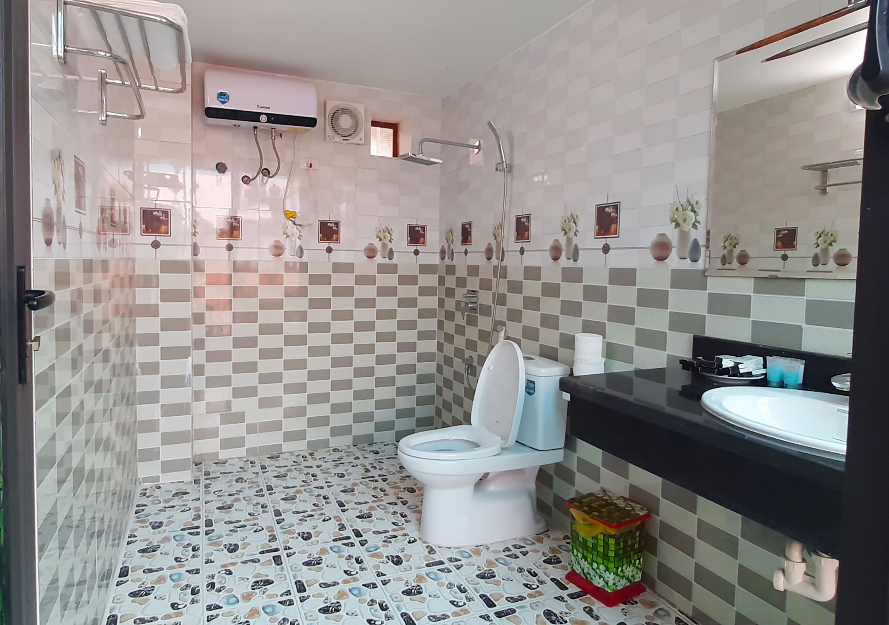 Une salle de bain avec des toilettes blanches, un lavabo noir et un miroir au-dessus.