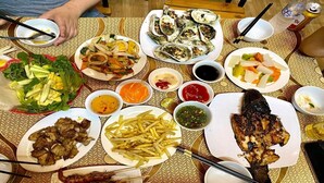 A table with various dishes including seafood, fries, and salads, suggesting a dining setting. - Tam Coc Koi Homestay (Nam Hoa Lu)
