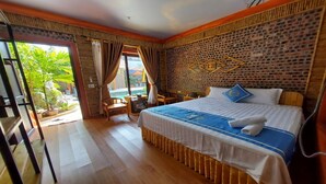 A hotel room with a large bed, a small desk, and a view of a pool. - Tam Coc Koi Homestay (Nam Hoa Lu)