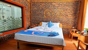 A hotel room with a bed, a wooden chair, a small table, and a decorative wall panel. - Tam Coc Koi Homestay (Nam Hoa Lu)