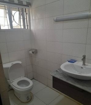 Een kleine, schone badkamer met toilet, wastafel en raam.
