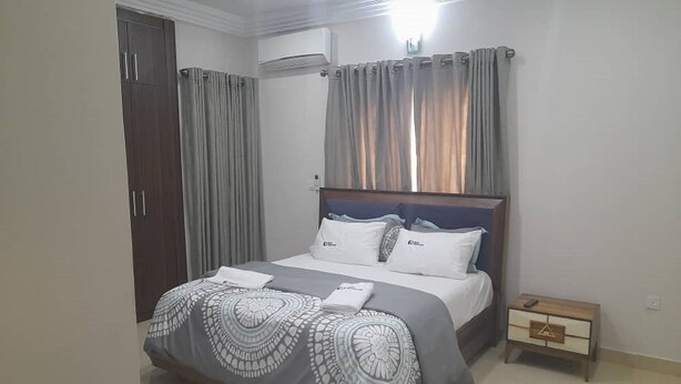 Een slaapkamer met een bed, gordijnen, een airconditioning en een nachtkastje.
