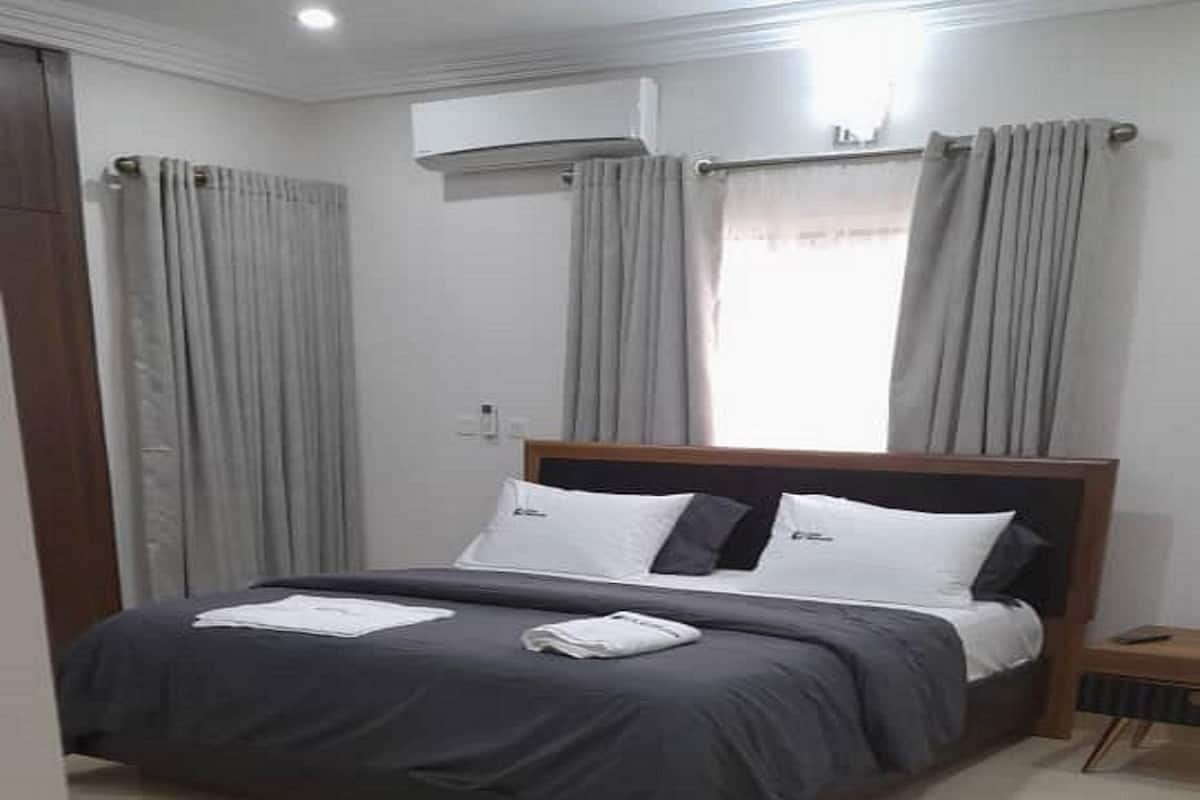A bedroom with a bed, curtains, and a window.