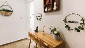Une pièce comprenant un bureau en bois, un miroir, une étagère avec des objets décoratifs et des éléments décoratifs muraux, notamment une guirlande en forme de cœur et un panneau circulaire portant le mot «Relax».