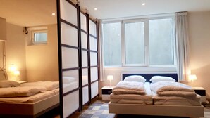 A hotel room with a large bed, two bedside tables, a window with curtains, and a sliding door. - Villa Martensplek with sauna, 10 pers + 2 toddlers (Tiendeveen)