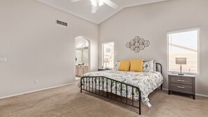 Un dormitorio con cama, mesita de noche, cómoda y ventilador de techo.