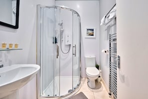 A modern bathroom with a glass-enclosed shower, a white sink, and a toilet.