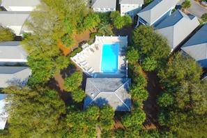 Vista aérea de una zona residencial con piscina, rodeada de árboles y viviendas.