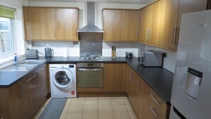 Cocina compacta con armarios de madera, lavadora, estufa y refrigerador.