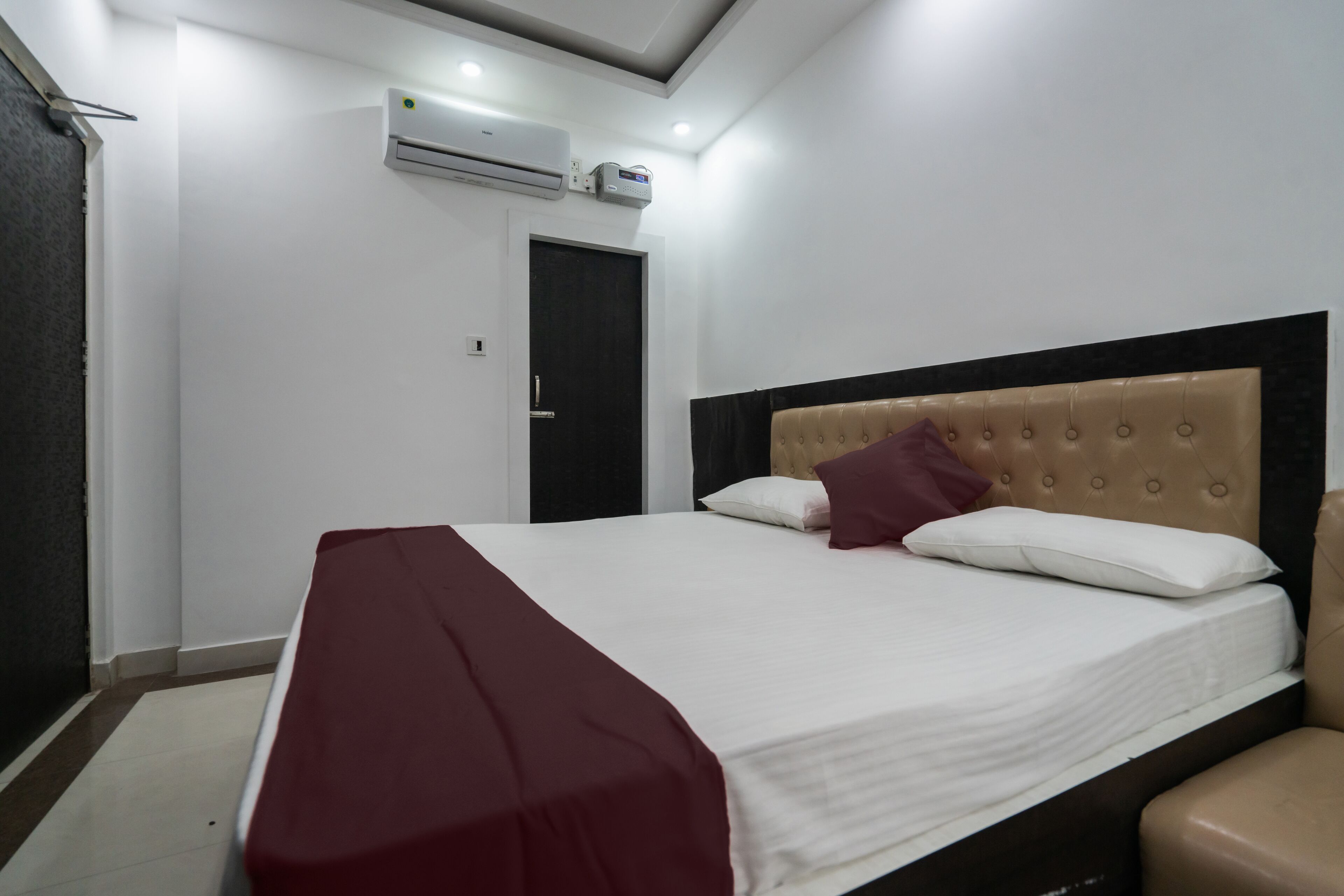 Una habitación de hotel con cama, sillón, puerta y aire acondicionado.