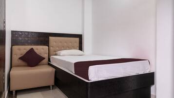 Un dormitorio con cama, un pequeño sofá y un cabecero decorativo.