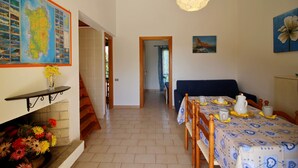 Een eetruimte met een tafel gedekt voor vier personen, een kaart aan de muur en een trap naar een andere kamer.