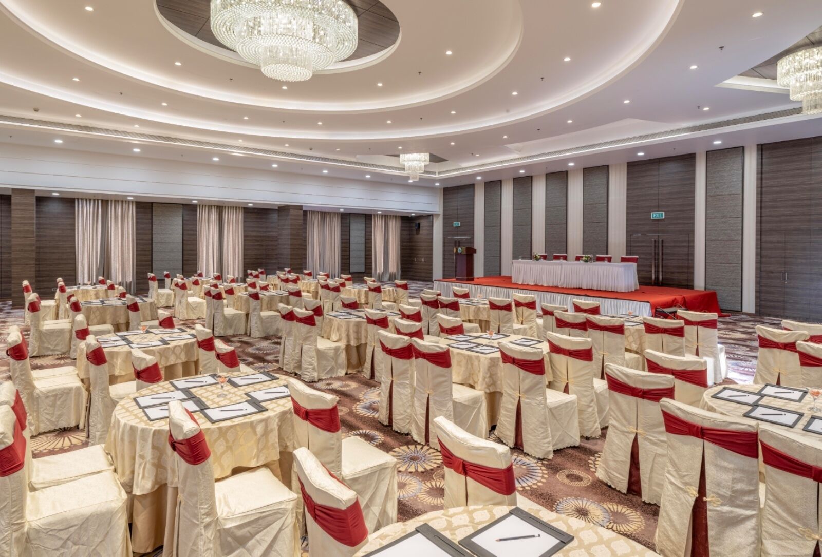 A large conference room with round tables, chairs, and a stage.