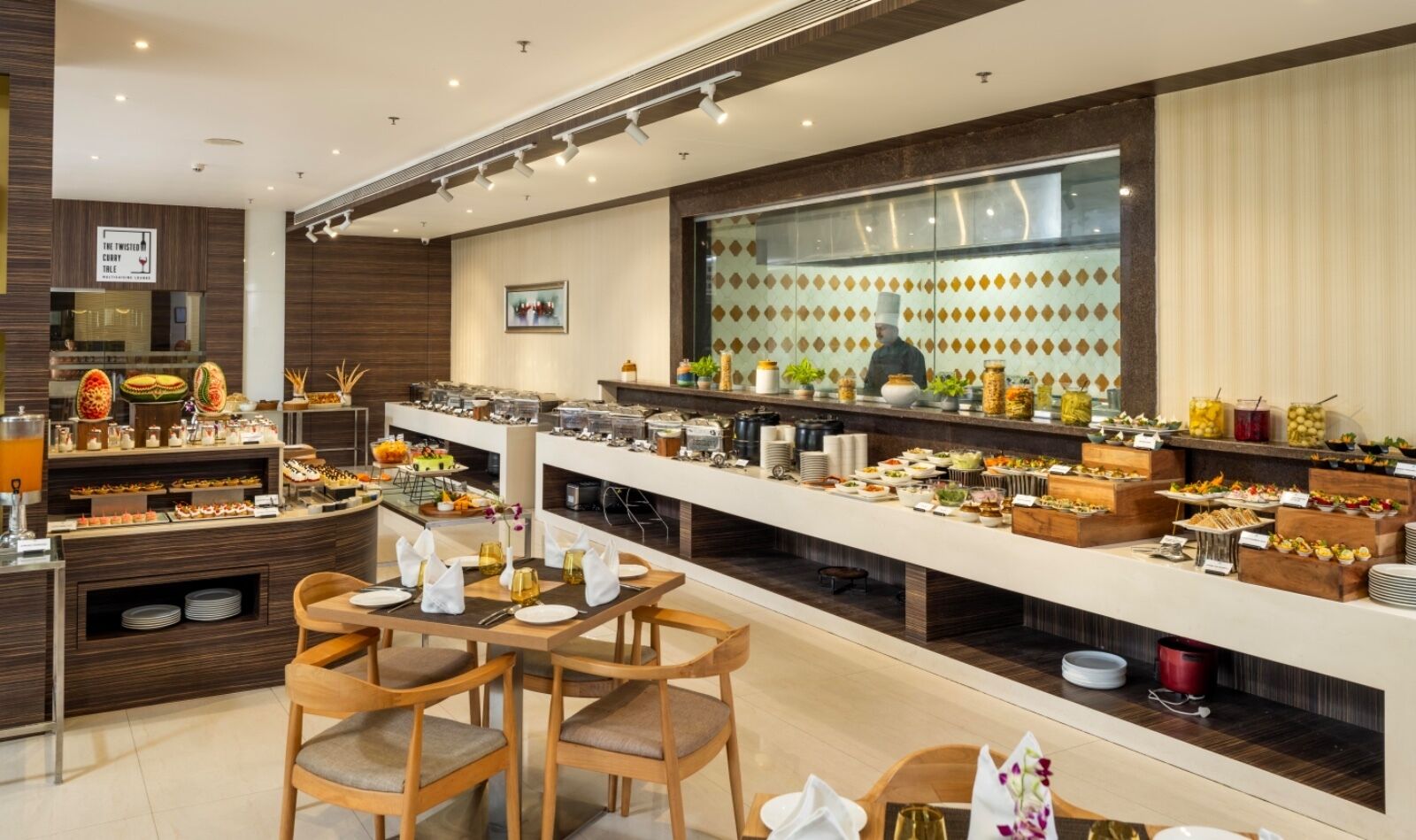 A modern buffet with a variety of food items and a chef in the background.