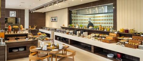 A modern buffet with a variety of food items and a chef in the background.