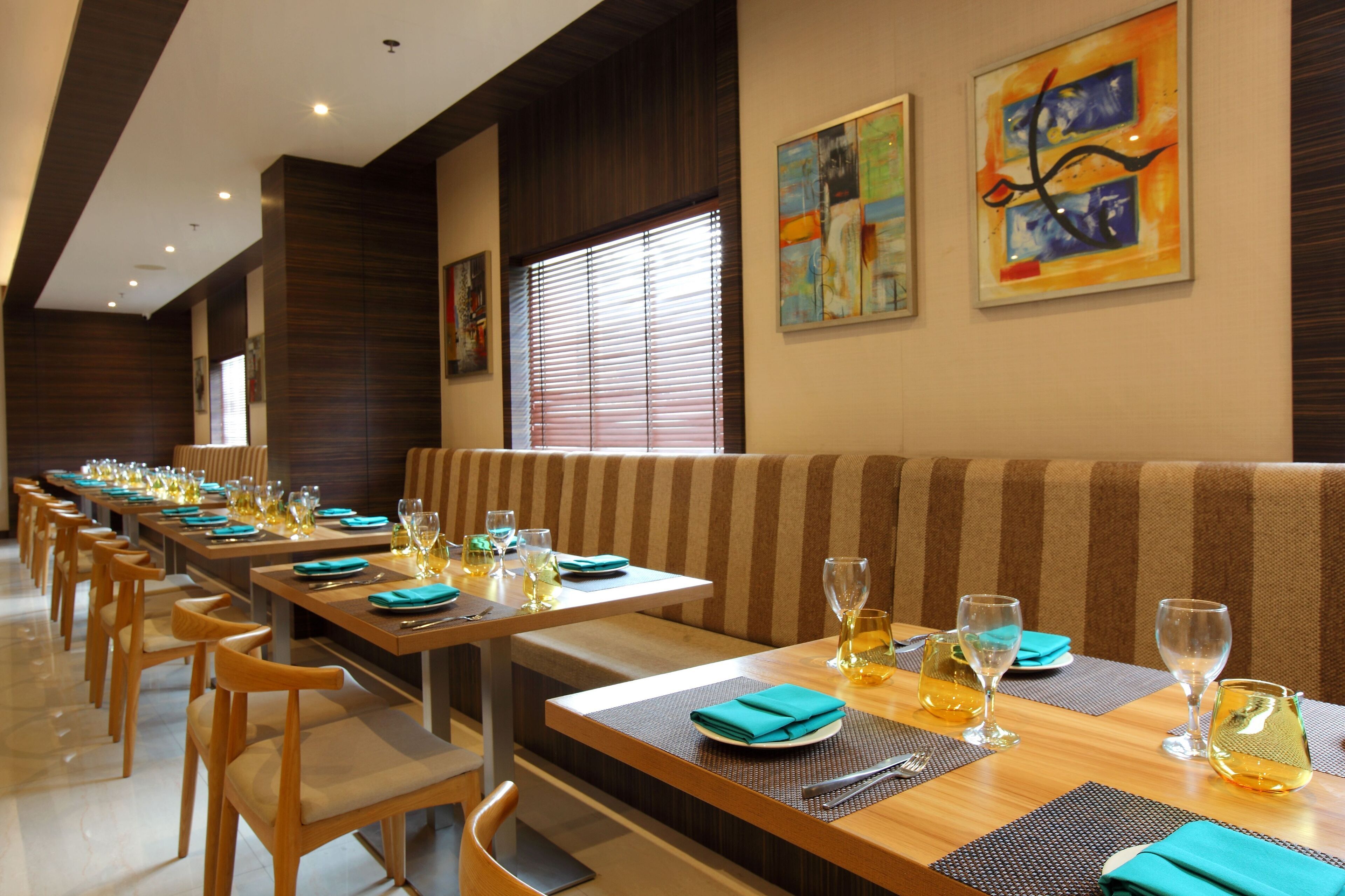 A restaurant with long tables, striped booths, and artwork on the walls.