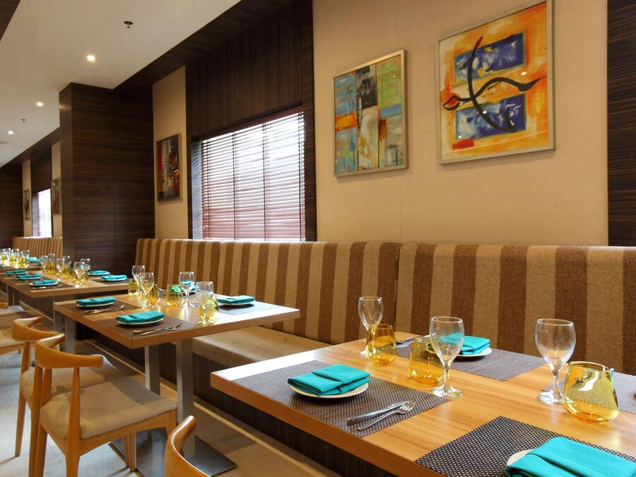 A restaurant with long tables, striped booths, and artwork on the walls.
