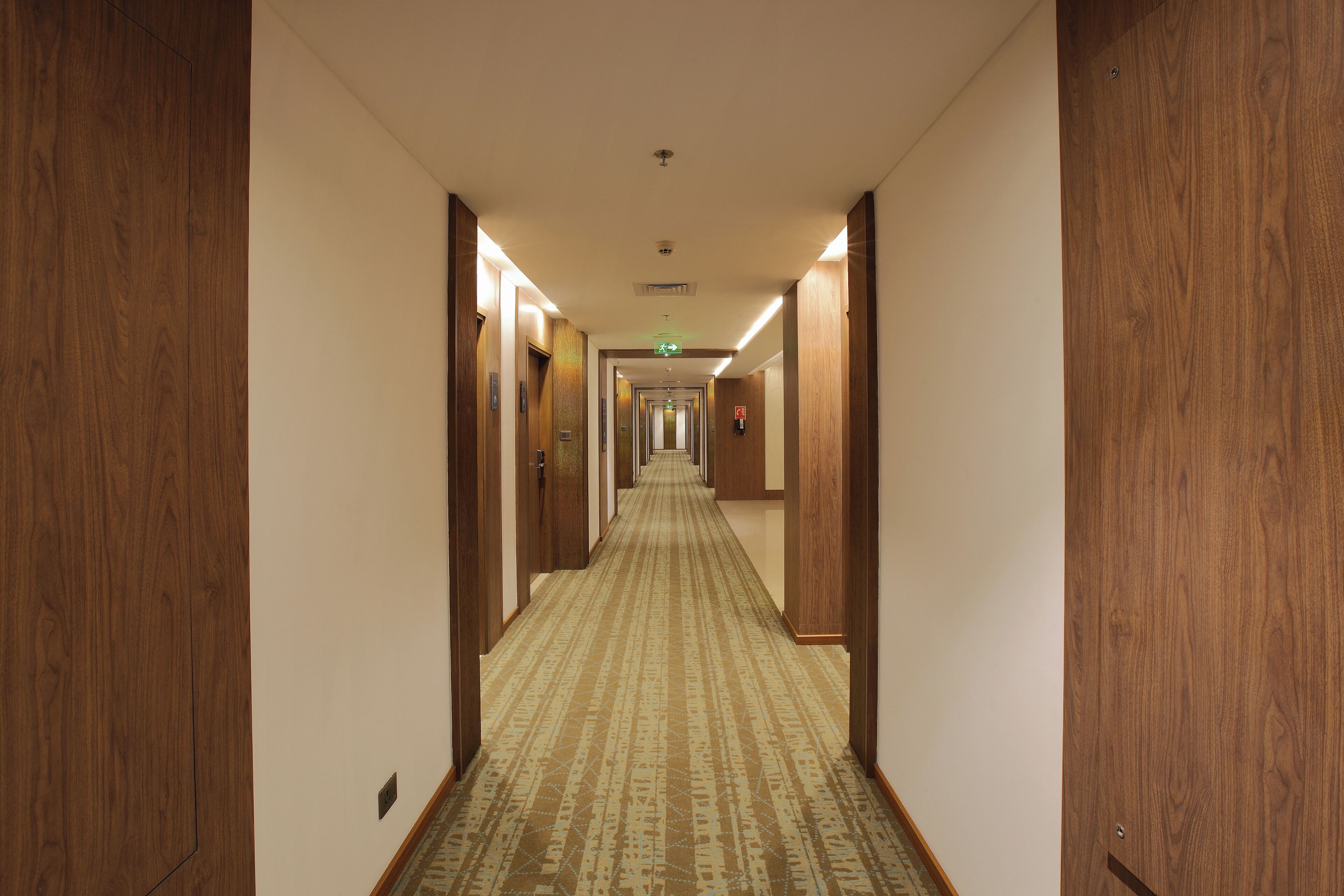 Ein Hotelgang mit Holztüren und einem gemusterten Teppich.