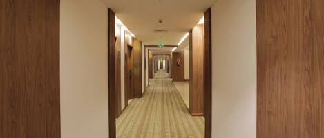 Ein Hotelgang mit Holztüren und einem gemusterten Teppich.