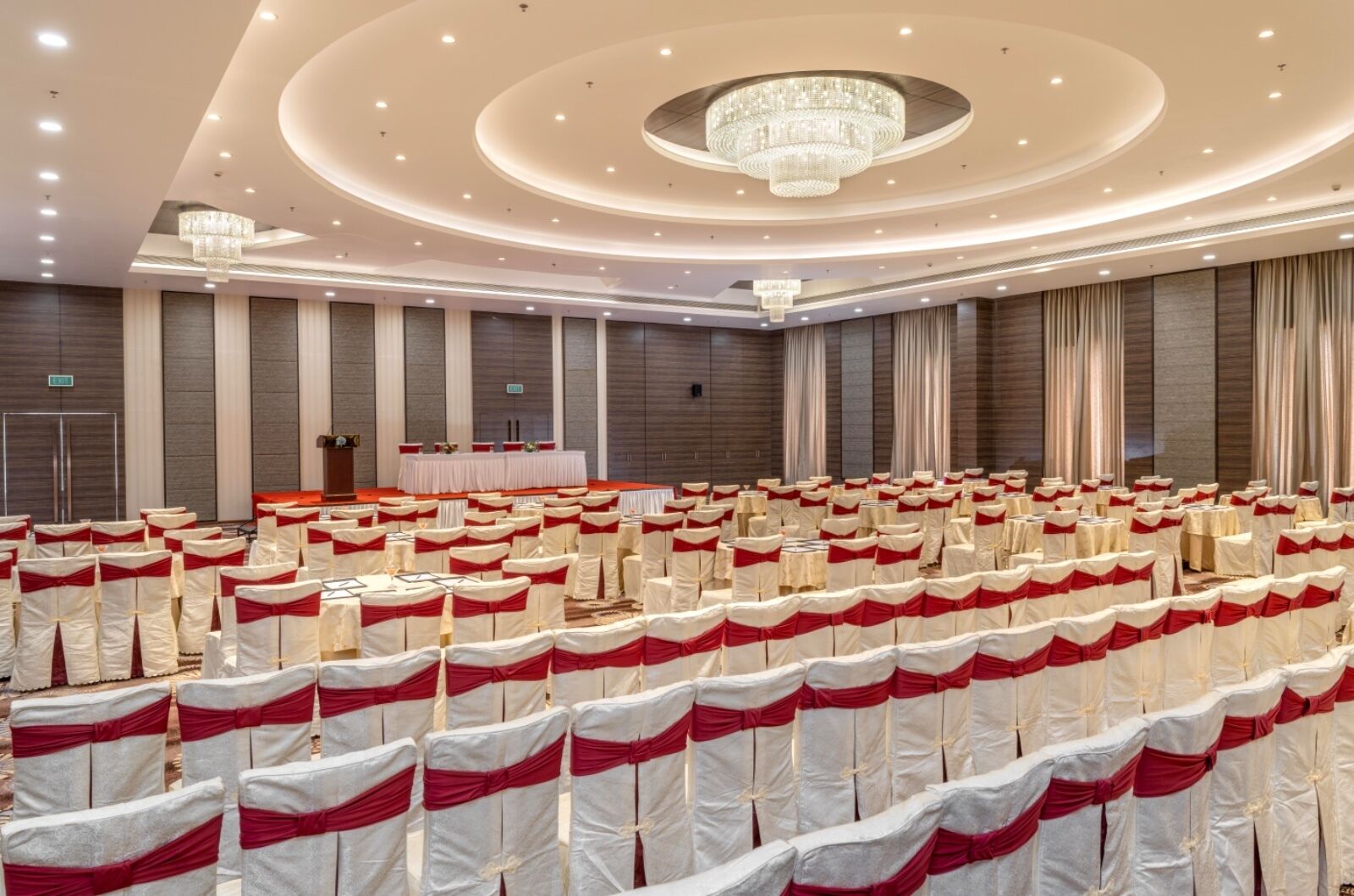 Une grande salle de conférence avec des rangées de chaises, une scène dotée d’un pupitre et un lustre.