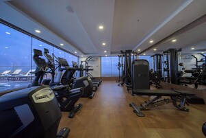 A gym with cardio machines, weightlifting equipment, and benches.
