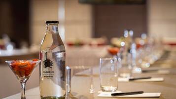 Een gedekte tafel met een fles drank, een martini glas en een glas water.