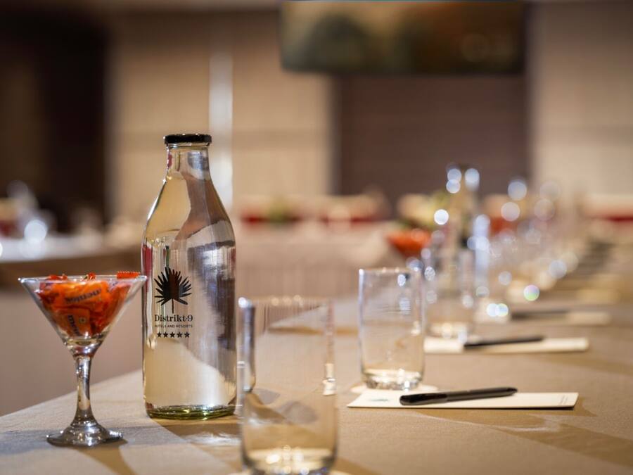 Een gedekte tafel met een fles drank, een martini glas en een glas water.