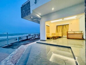 Eine moderne Hotelhalle mit Blick auf den Strand, eine Sitzecke mit gelben Stühlen und eine Rezeption.
