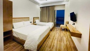 Ein Hotelzimmer mit einem großen Bett, einem Schreibtisch, einem Sessel, einem Fernseher und einem Deckenventilator.