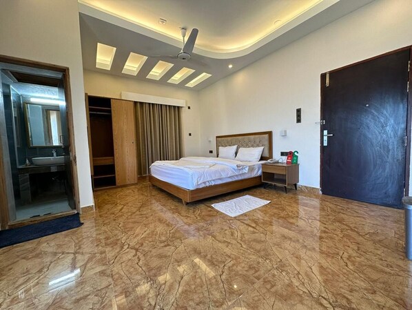 Ein modernes Schlafzimmer mit einem großen Bett, einem Kleiderschrank, einem Schminktisch und einem Deckenventilator.