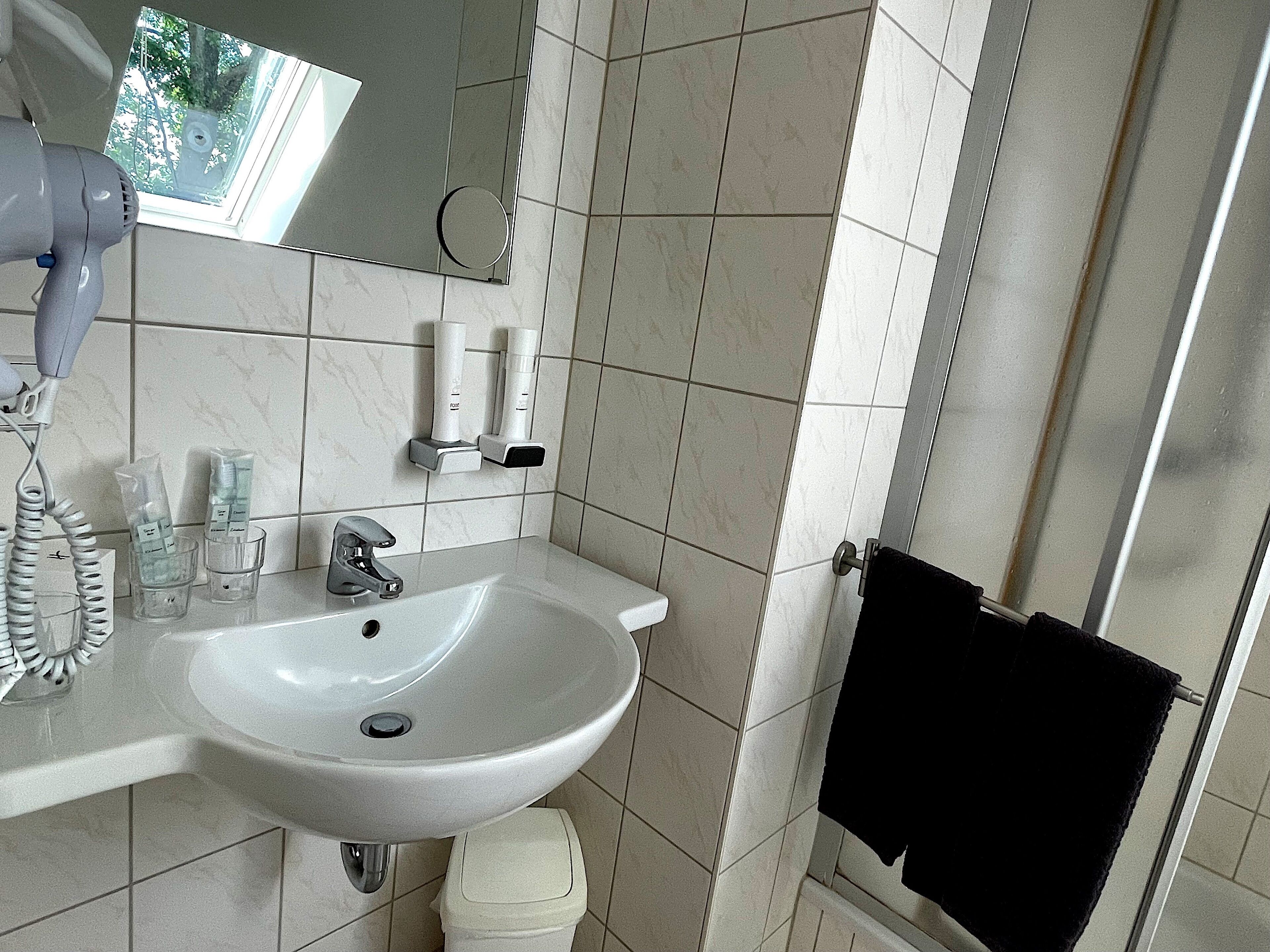 A bathroom with a white sink, a mirror, a hairdryer, and a towel rack.