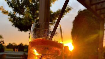 Ein Glas Eisgetränk mit Trinkhalm auf einem Holztisch, im Hintergrund ein Sonnenuntergang.