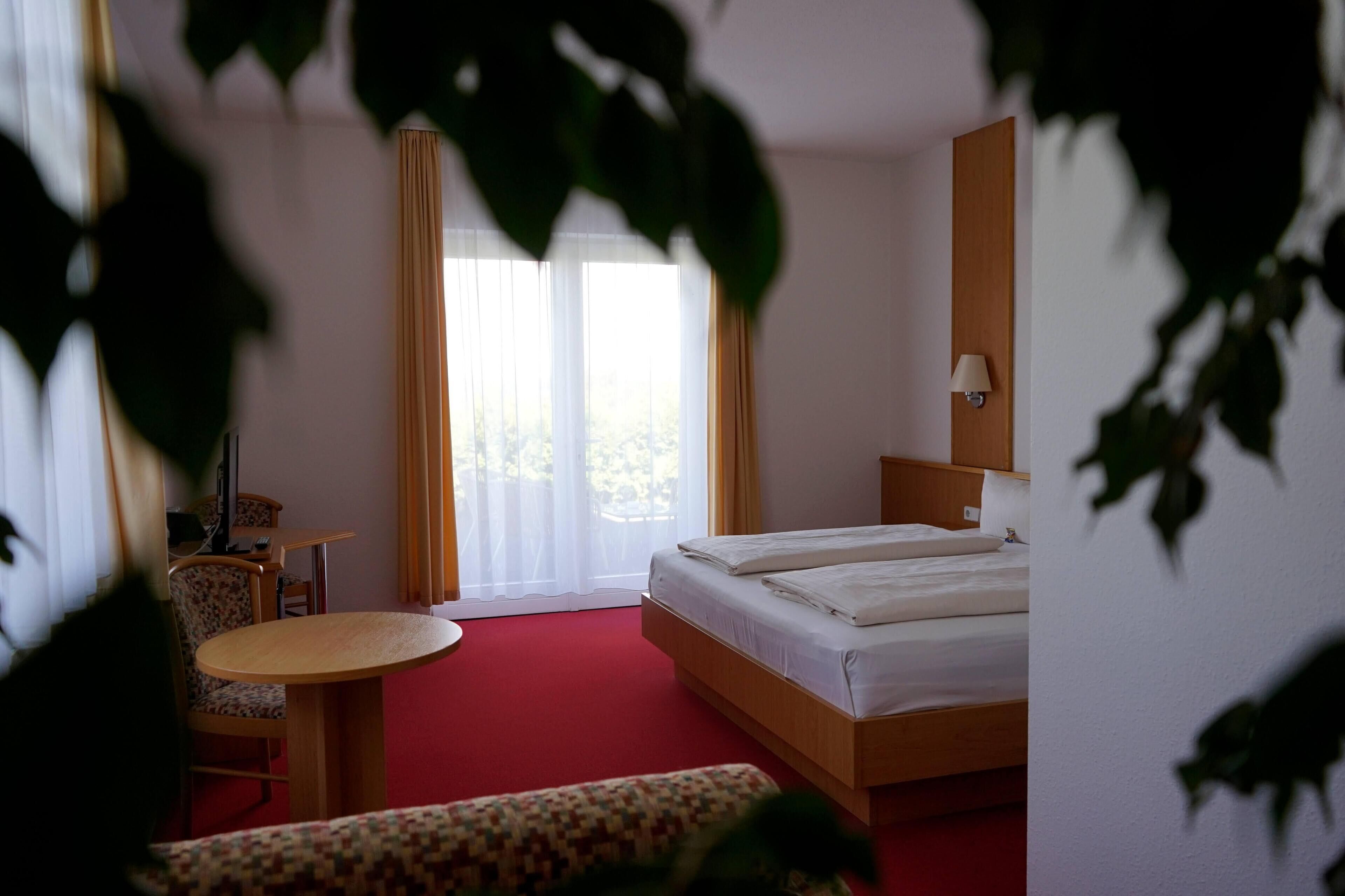 Una habitación de hotel con cama, escritorio, silla y una mesita.