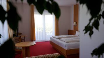 A hotel room with a bed, a desk, a chair, and a small table.