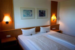Two single beds with crisp linens and lamps on bedside tables create a cozy retreat.