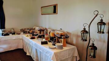 A buffet setup with various food items and a coffee station, a mirror on the wall, and decorative lanterns.