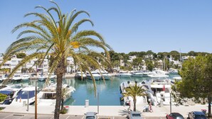 A marina with boats docked, palm trees, and a clear blue sky.