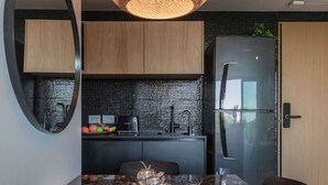 A modern kitchen with a black tiled backsplash, wooden cabinets, a stainless steel refrigerator, and a marble countertop with a fruit bowl. - MOT Rentals Armenia Luxury Lofts Mansion Botanico (Palermo Soho)