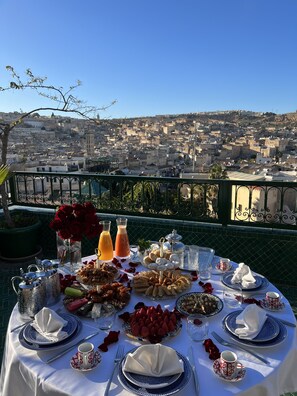 A table set for a meal with a city view in the background. - Palais de Fès Suites & Spa (Fes)