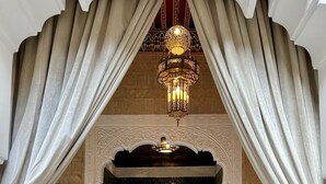 An ornate room with a patterned floor, a green door with intricate designs, and a chandelier. - Palais de Fès Suites & Spa (Fes)