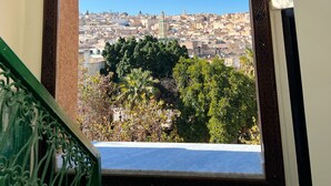 A view from a balcony with ornate metal railings and hanging lanterns, overlooking a densely packed cityscape with traditional buildings. - Palais de Fès Suites & Spa (Fes)