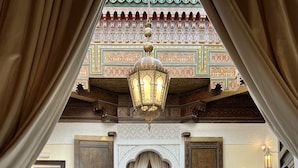 A luxurious room with a large bed, two armchairs, a coffee table, and a view of a traditional Moroccan interior. - Palais de Fès Suites & Spa (Fes)