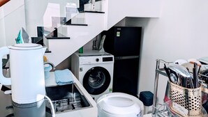 Cocina compacta con lavadora, refrigerador y cafetera.