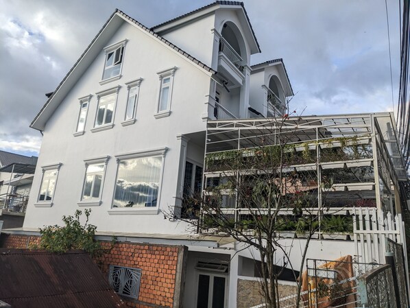 A two-story building with a white facade, multiple windows, and a balcony. - VilLa 62 (Da Lat)