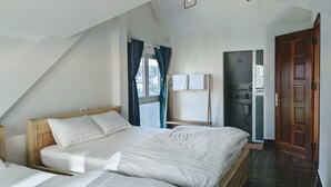 Un dormitorio con una cama grande, cabecera de madera, ventana con cortinas y vistas al exterior.