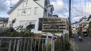 Un edificio de dos pisos con fachada blanca, múltiples ventanas y un balcón.
