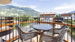 Ein Balkon mit Tisch und Stühlen, der einen Blick auf eine Berglandschaft bietet.