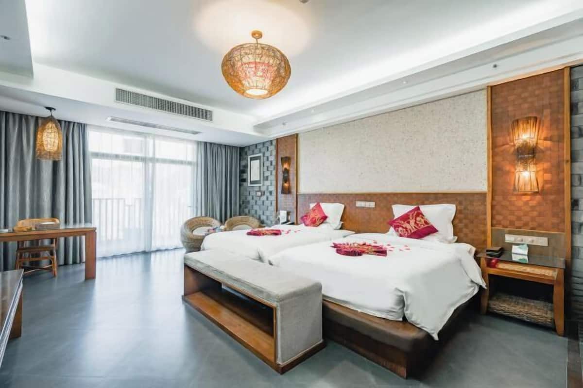 A hotel room with a large bed, bedside tables, a desk, and a window with curtains.