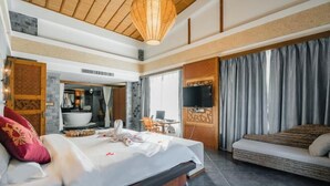 Ein Hotelzimmer mit Bett, Sofa, Fernseher, Badezimmer und Essbereich.